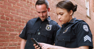 two police officers gaze at a phone screen